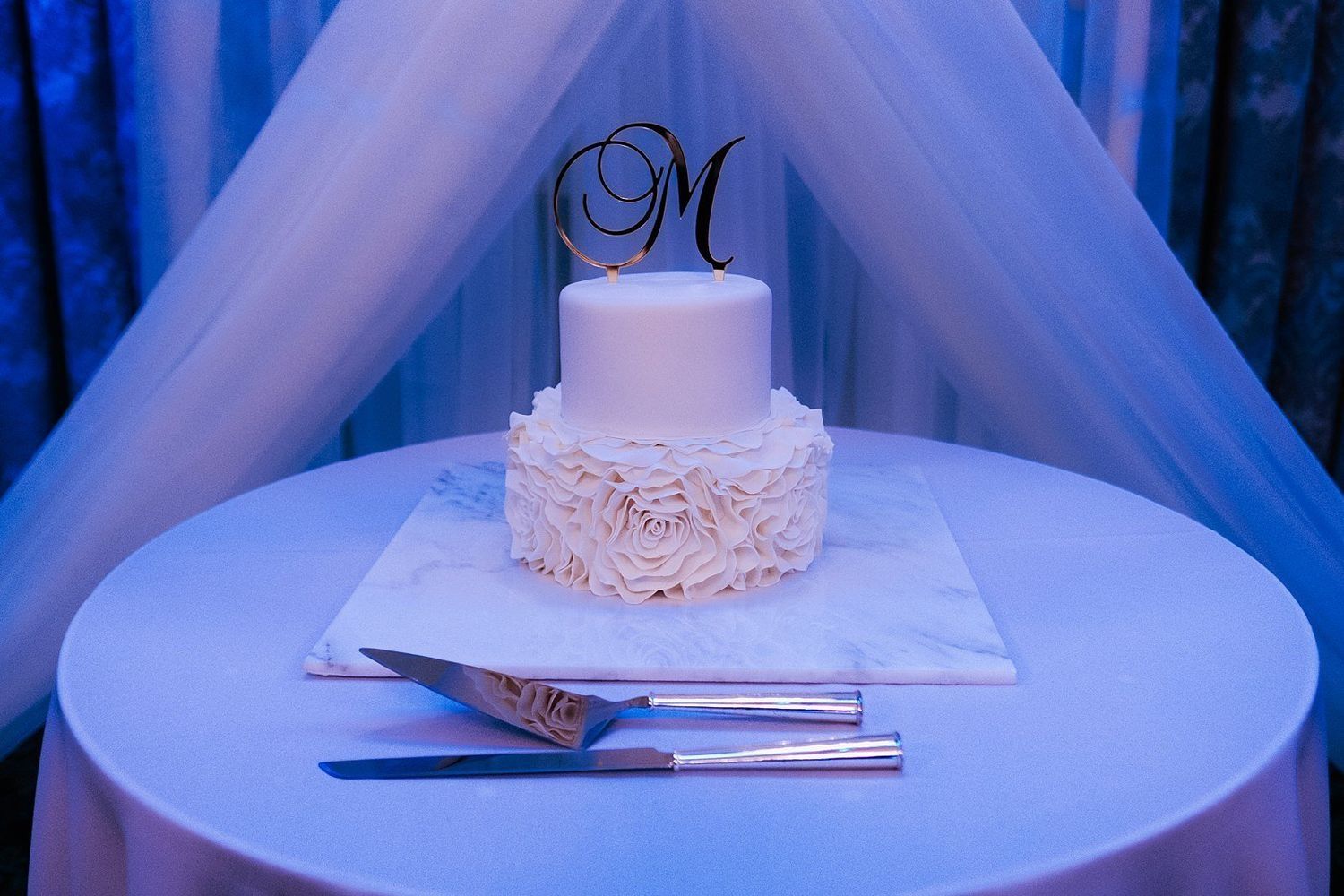 Luxury five-tier wedding cake with elegant floral decor and high-end lighting at McKay Ballroom.