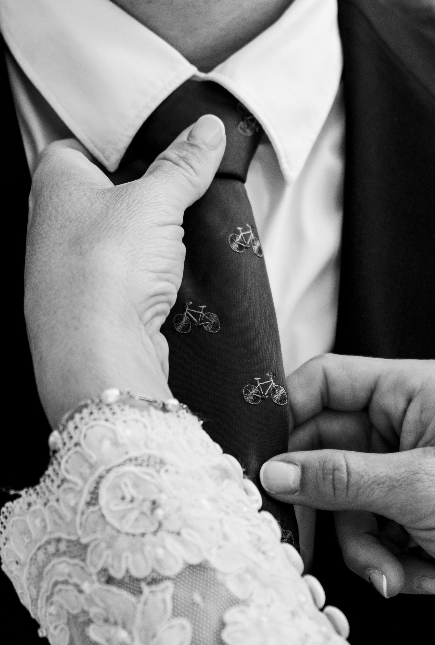 Detalle editorial en blanco y negro de la corbata de bicicletas de Jose y manos de Alejandra en el Pinar del Rey