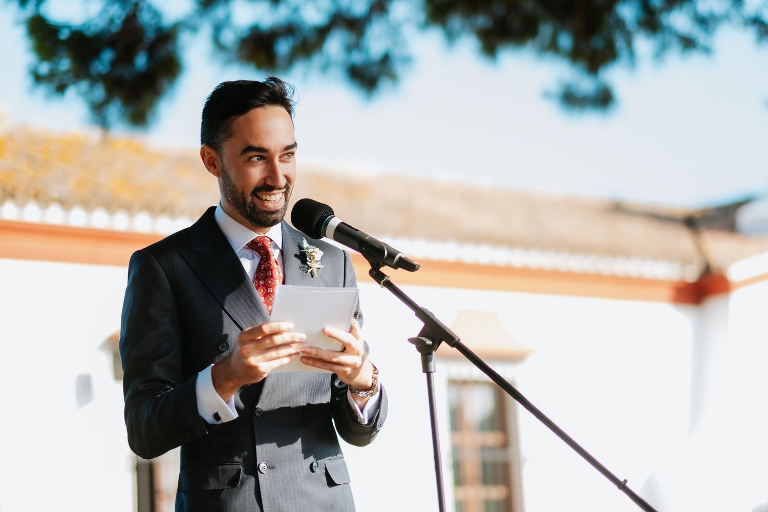 Wedding guest delivers emotional speech at outdoor reception while holding paper notes, Roberto Pecino fotografo en Soto de Roma