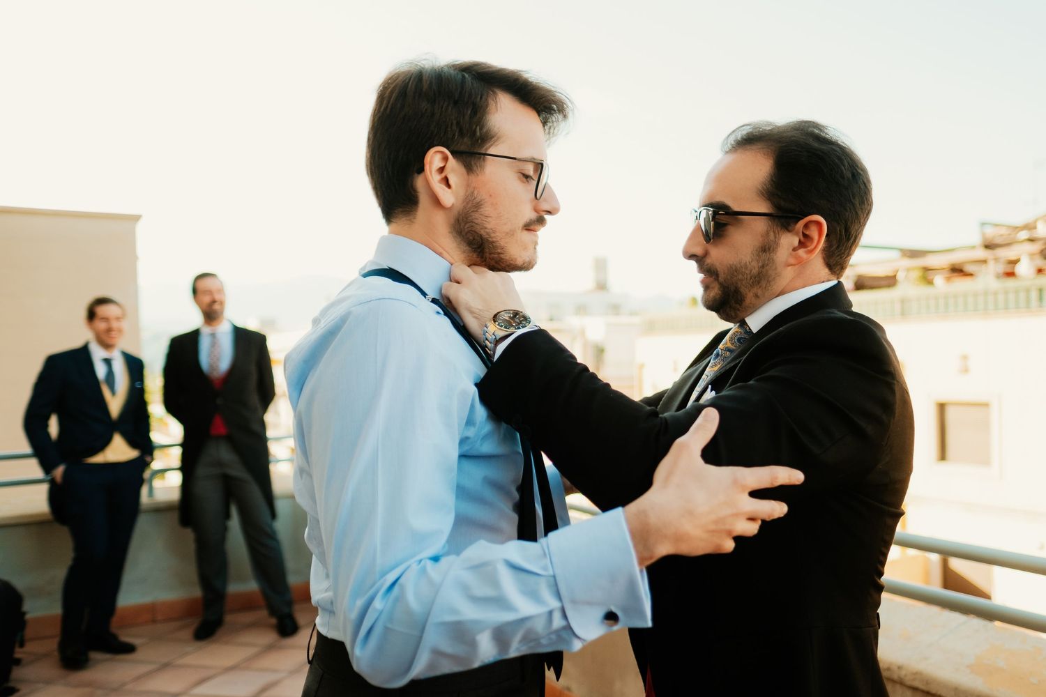 Invitado ajustando la corbata del novio en los preparativos