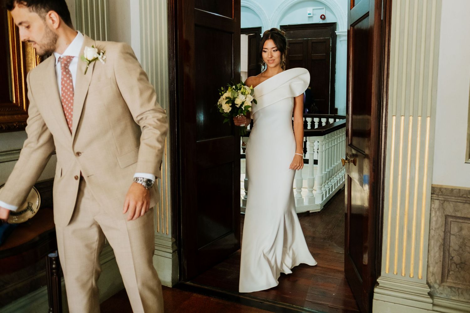 Wedding couple shares intimate moments in a grand hallway with classical architectural details.