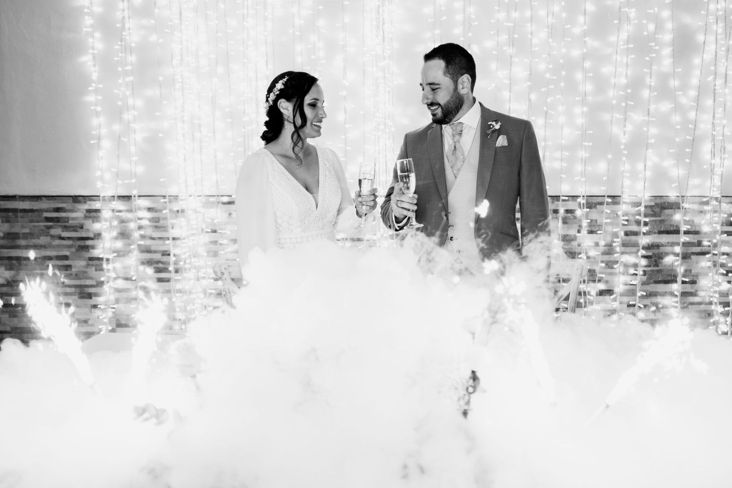 Black and white wedding portrait with twinkle lights creating a magical backdrop.