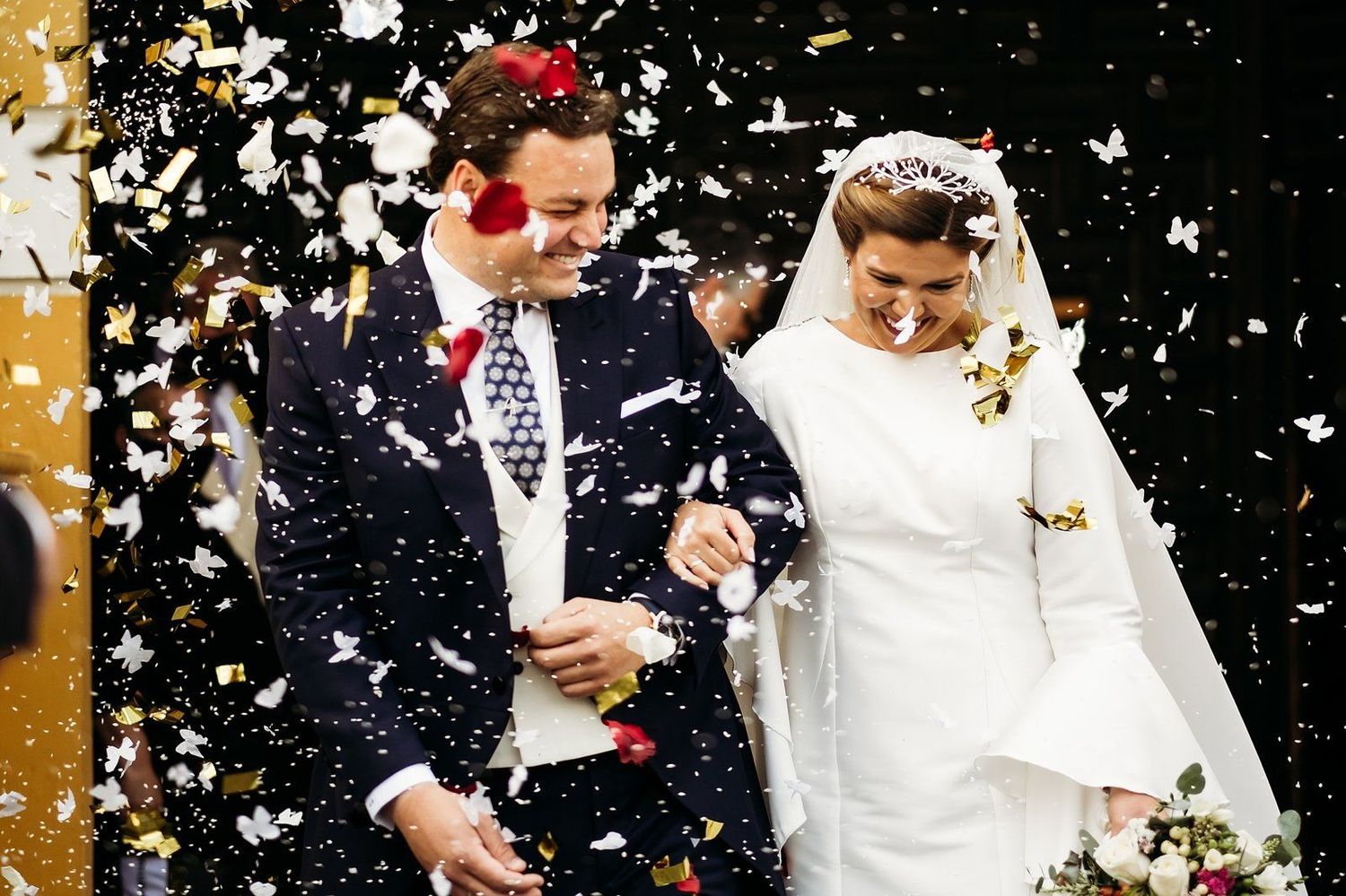 Salida de los novios de la iglesia bajo confeti blanco en Sevilla