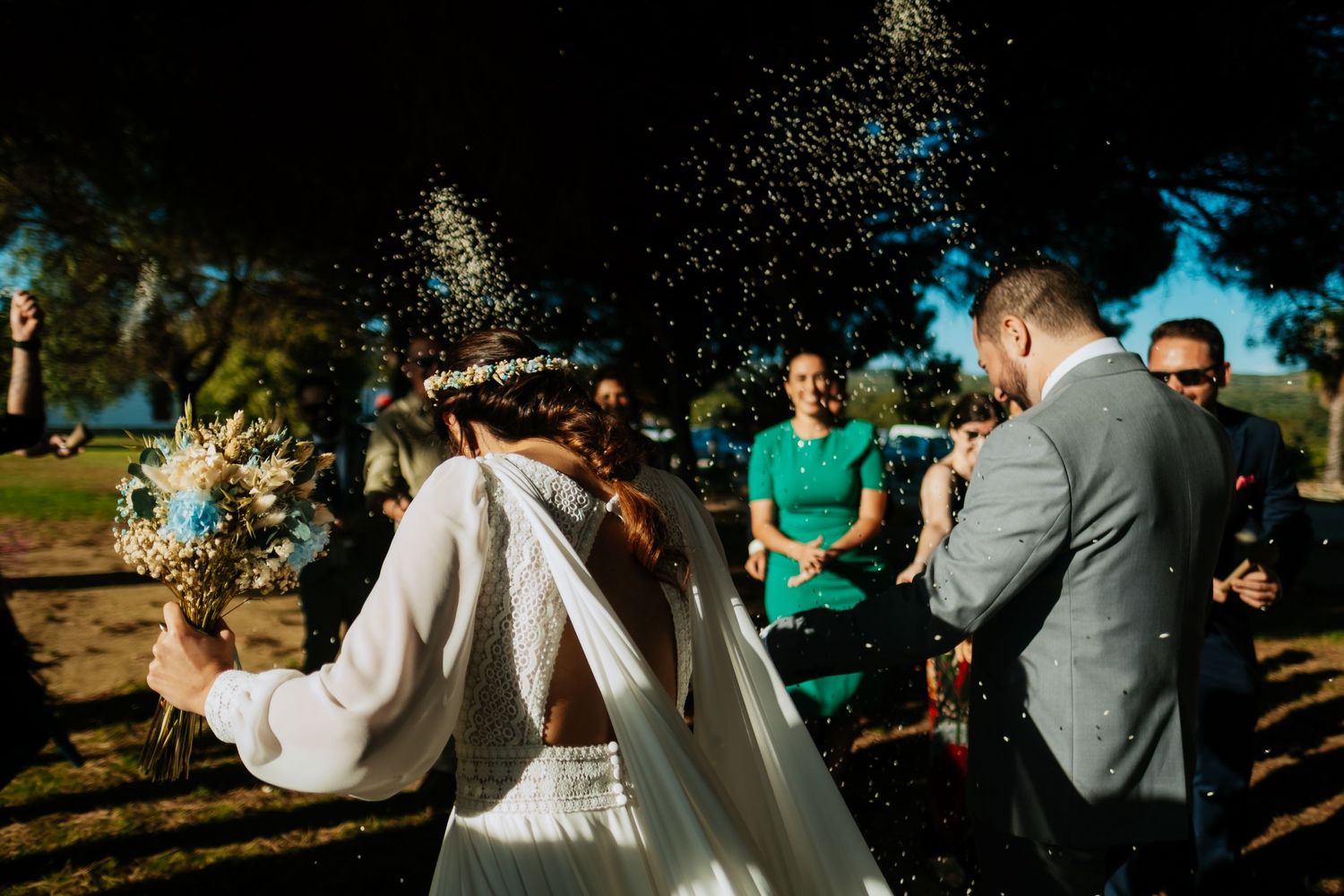 Wedding guests celebrate with confetti during an outdoor garden ceremony.