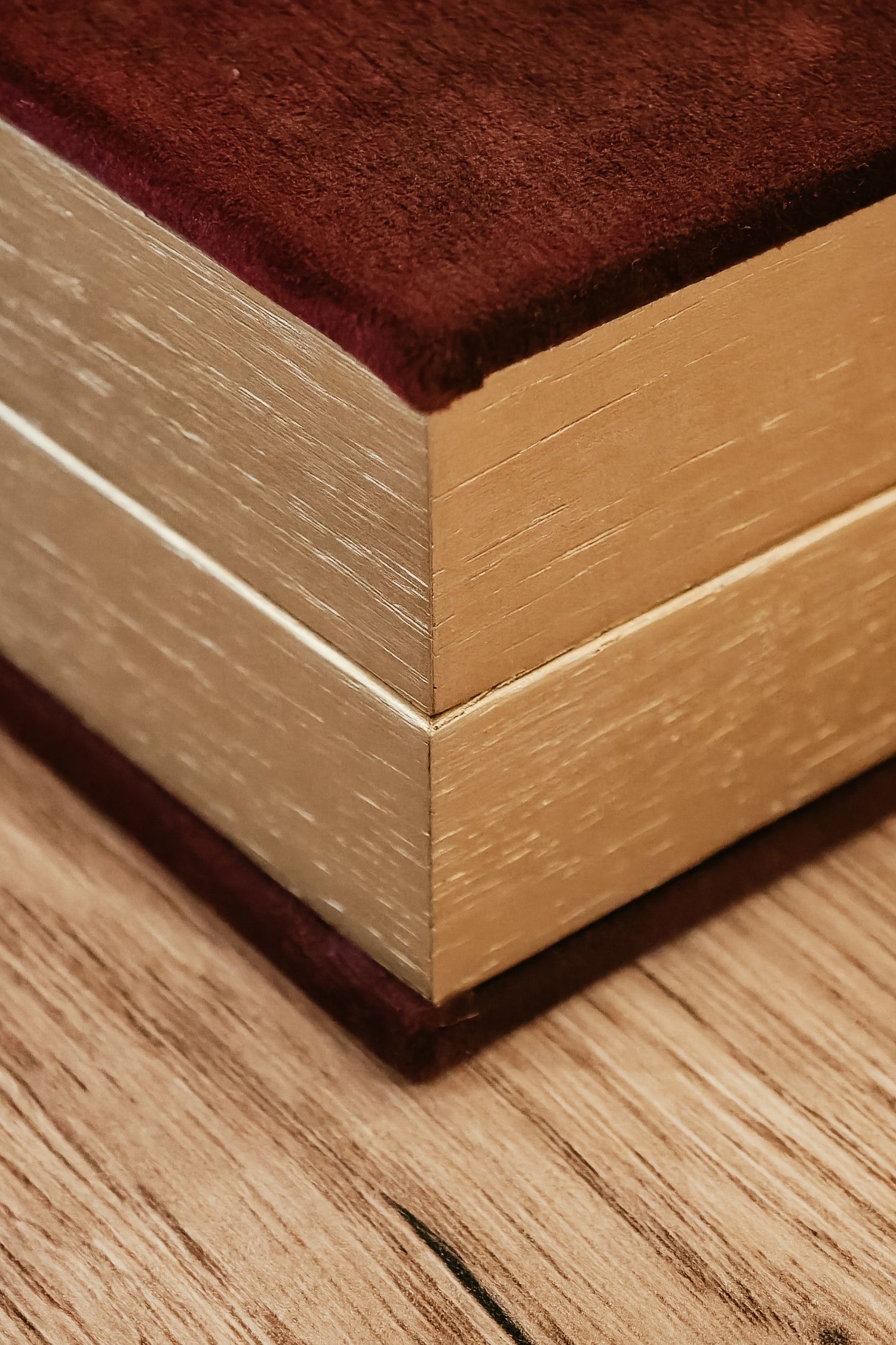 Close-up of a wooden baseboard corner with burgundy carpet showing textured grain details and sharp mitered joint.