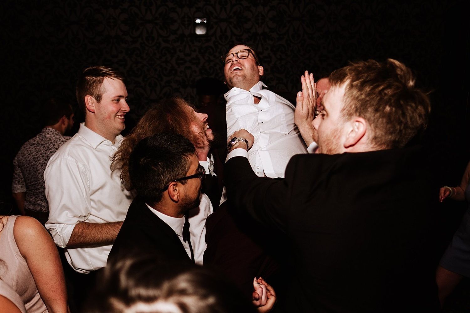 Ecstatic wedding celebration: guests jumping and cheering during the final party hours.