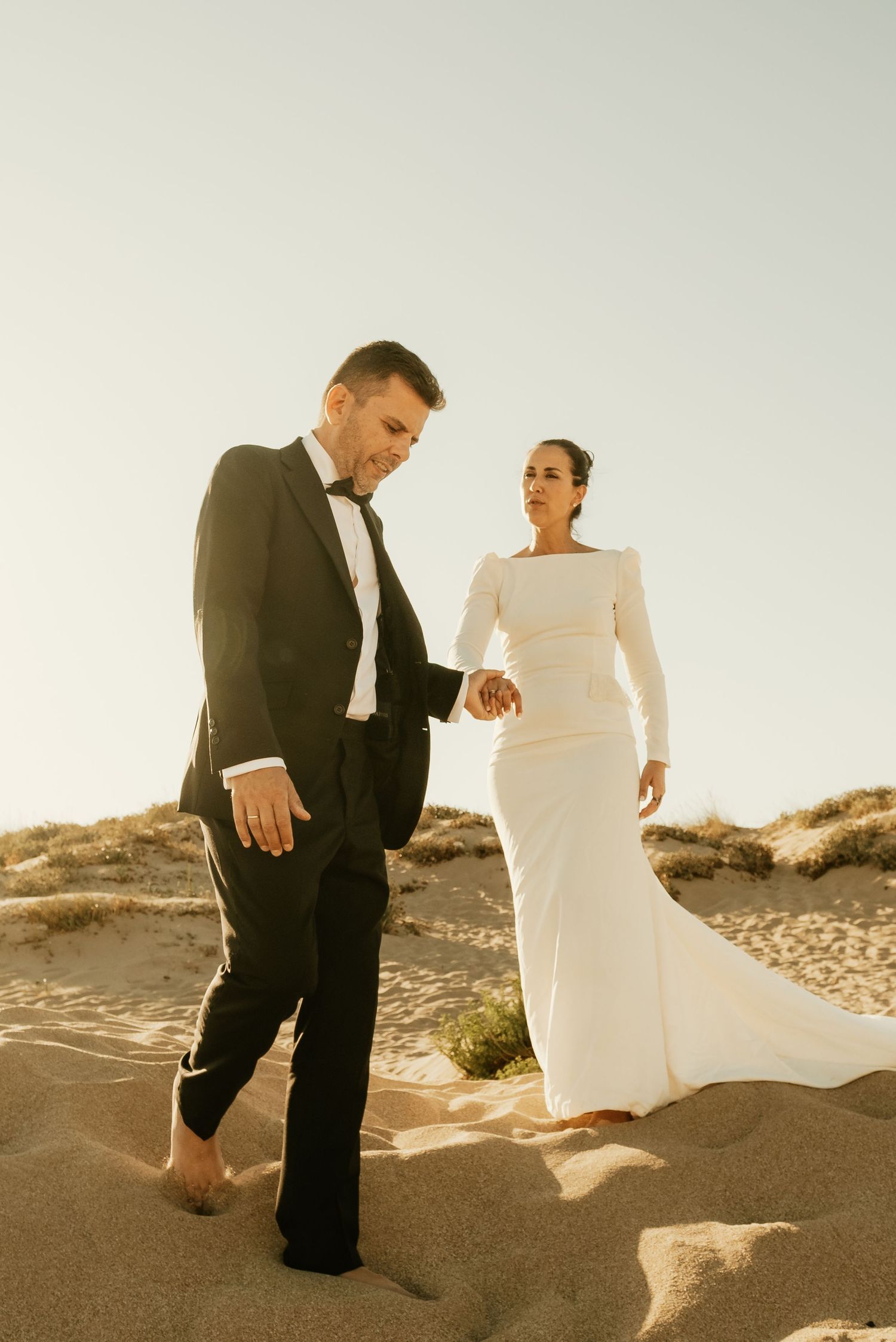 Fotografía de estética editorial de pareja bajando de la mano por la duna Faro de Trafalgar Laura y Fernando Roberto Pecino
