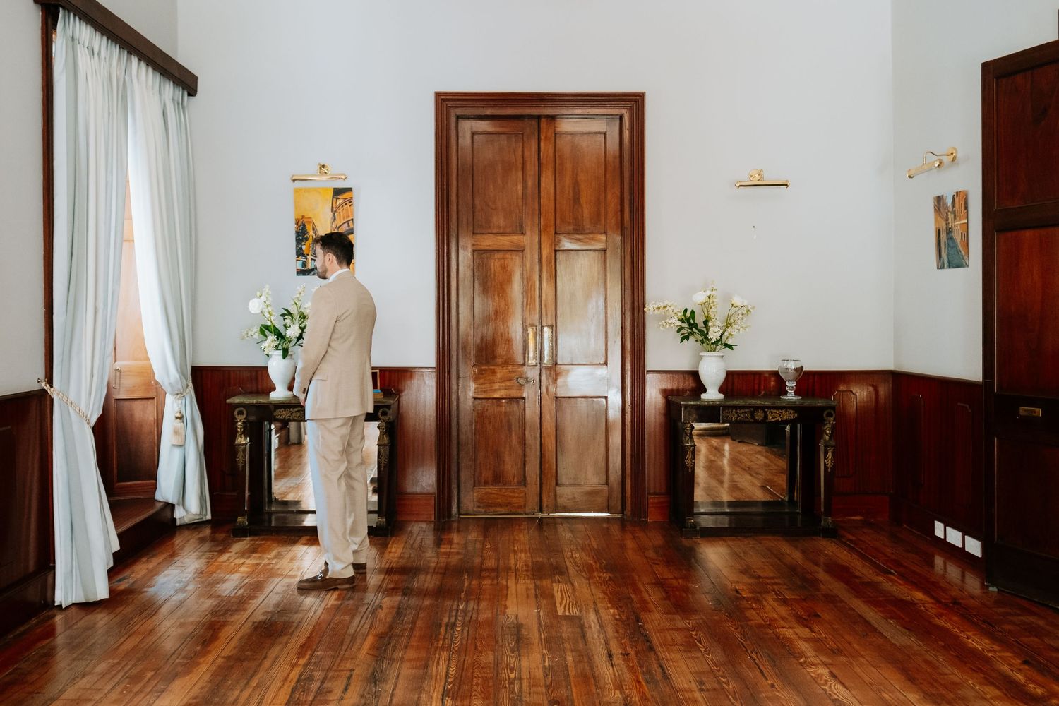 Elegant wooden doors and hardwood floors in a classic interior hallway with white walls and natural lighting. First look in Gibraltar