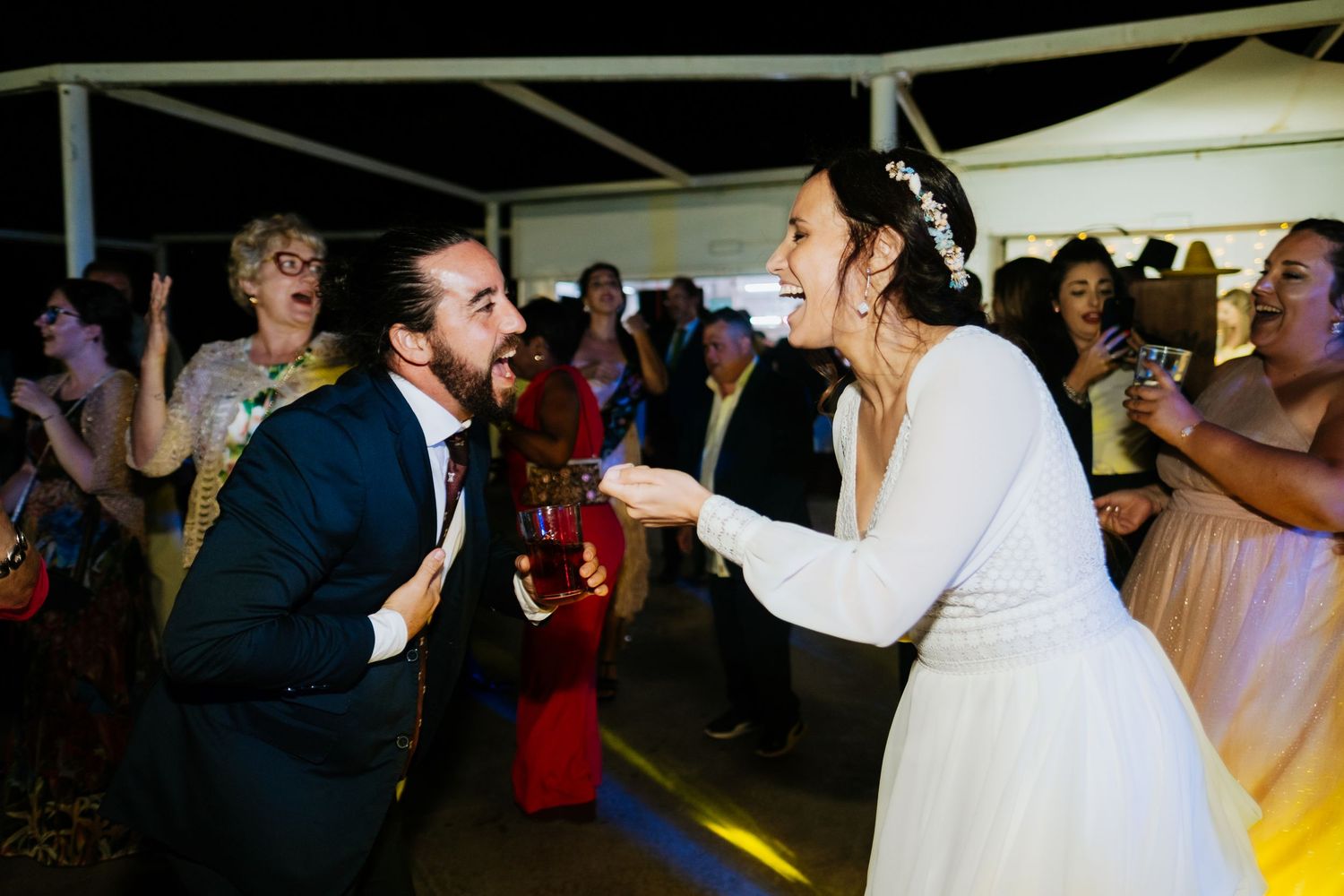 Wedding reception dance floor filled with guests celebrating under a tent.