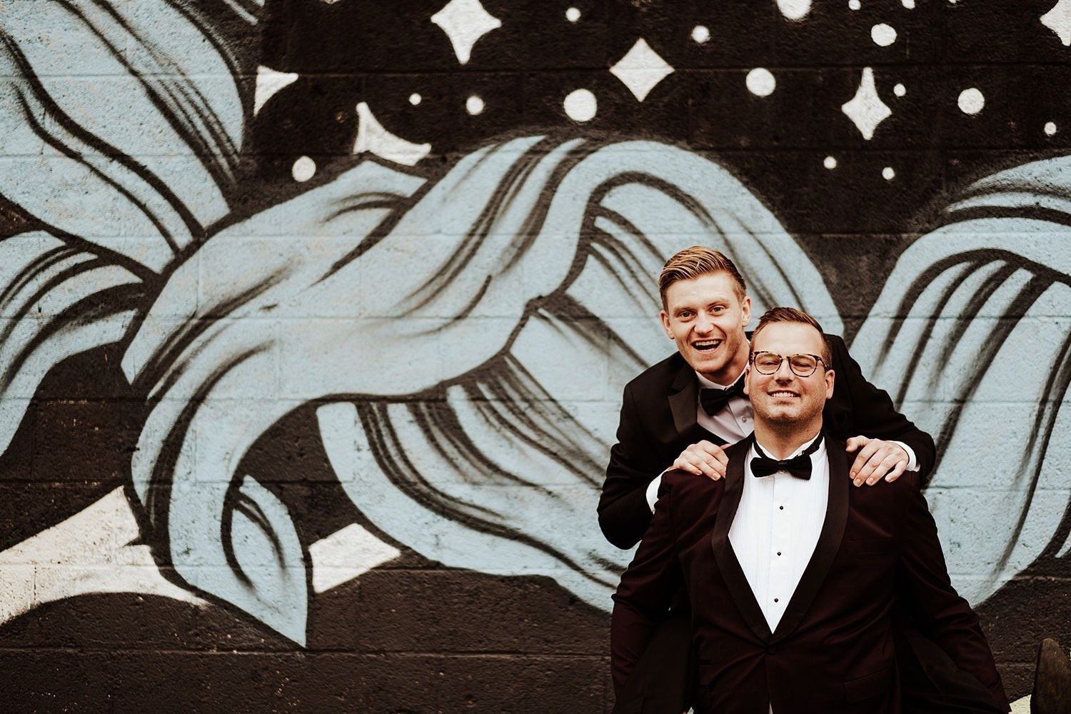 Karel and a wedding guest posing in front of vibrant urban graffiti in Grand Rapids