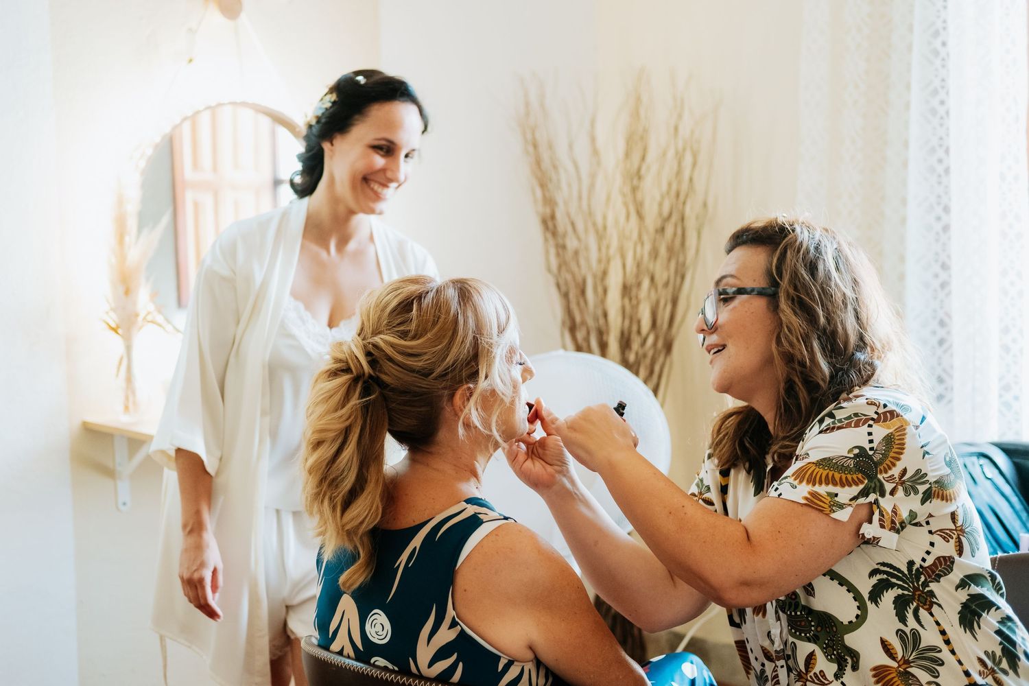Wedding party getting ready in a bright room with joyful expressions and laughter.