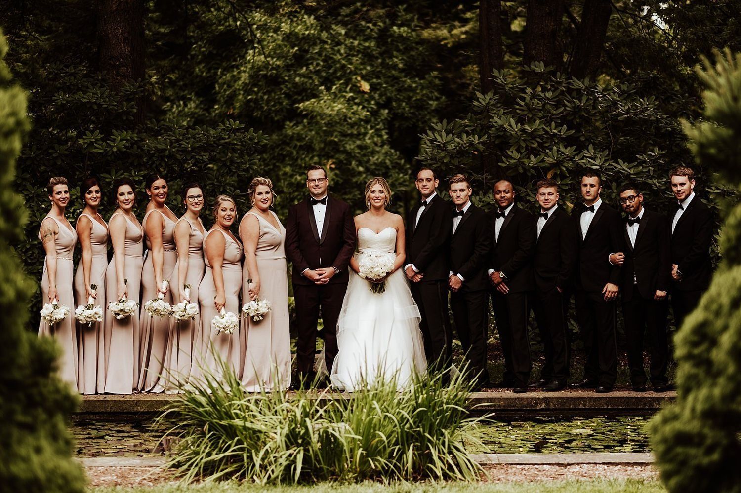 Symmetrical bridal party group shot in a lush Grand Rapids garden during the wedding session