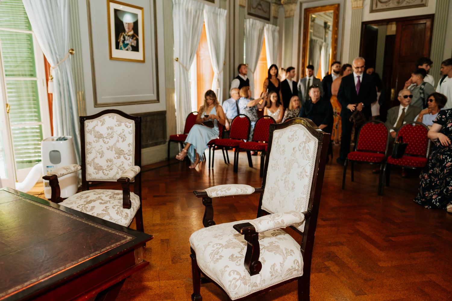Elegant wedding ceremony venue with white chairs and classic interior decor.
