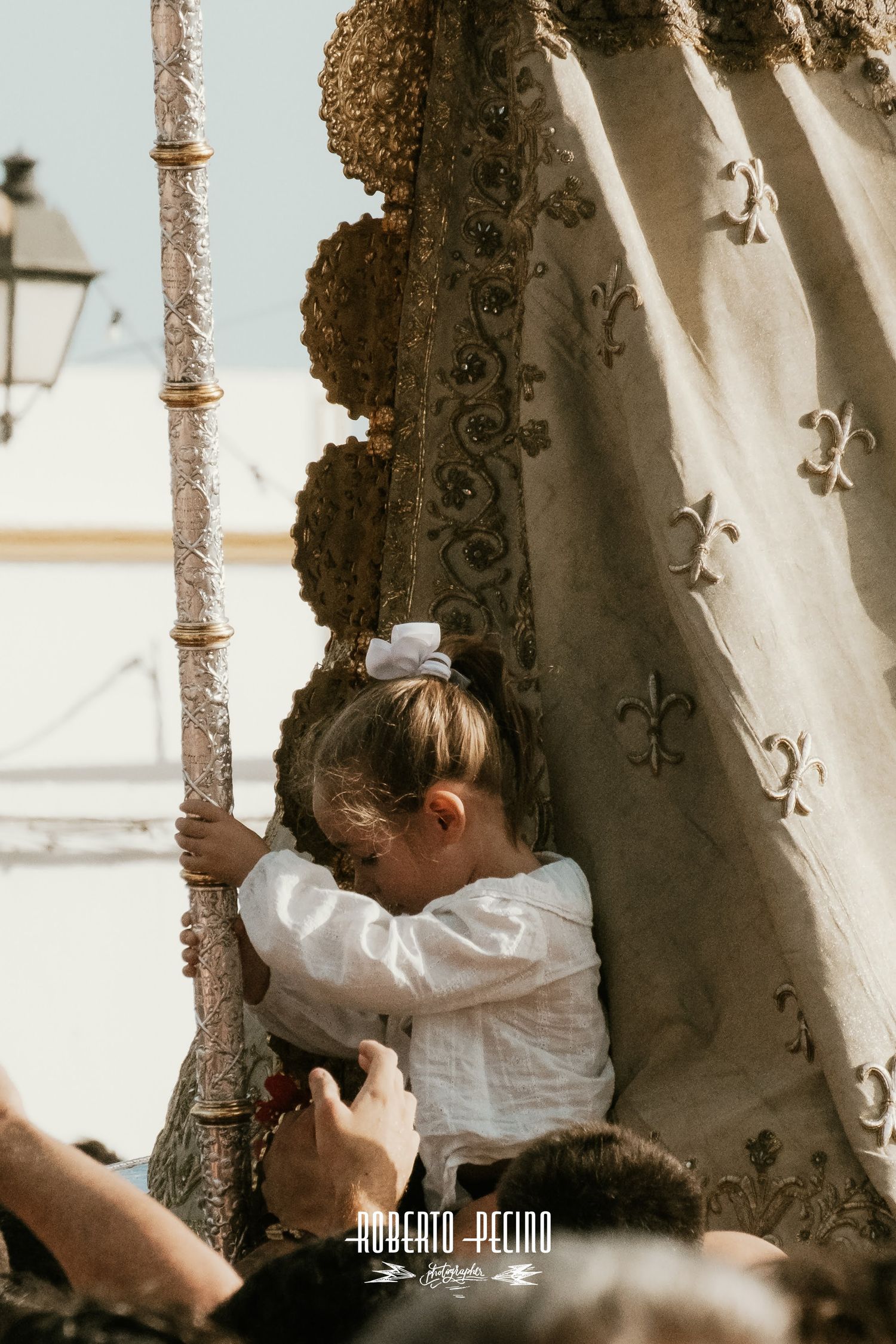 Reportaje de autor Romería del Rocío 2026, niña sentada a los pies de la Virgen, enfoque en fotografía de tradiciones, Roberto Pecino