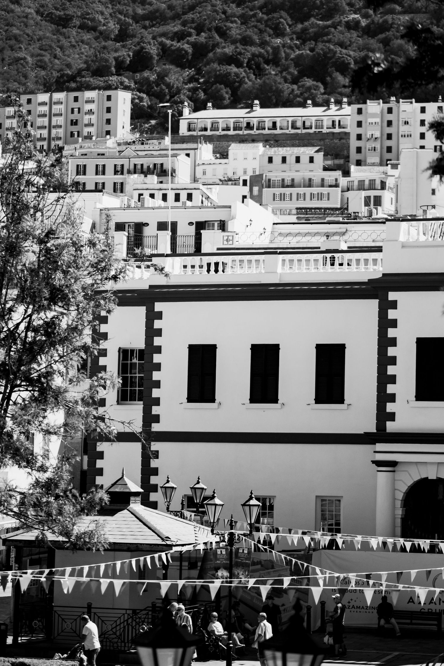 Black and white cityscape with bunting decorations and white buildings against mountainous backdrop.
