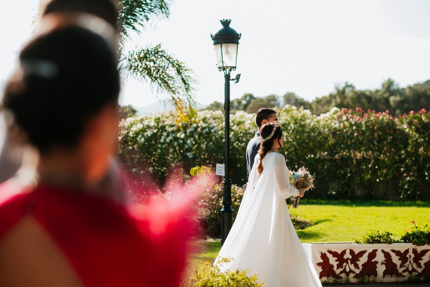 Wedding ceremony setup in a garden with white chairs and floral decorations at sunset.