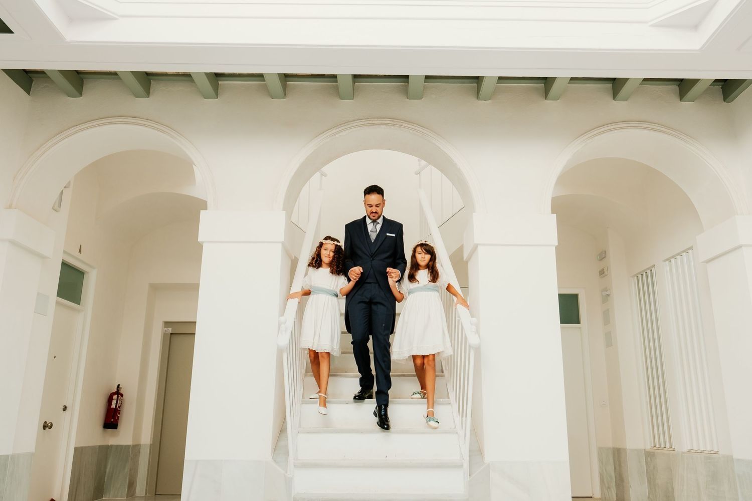 Hijas del novio caminando con su padre en el patio de una casa antigua de Cádiz