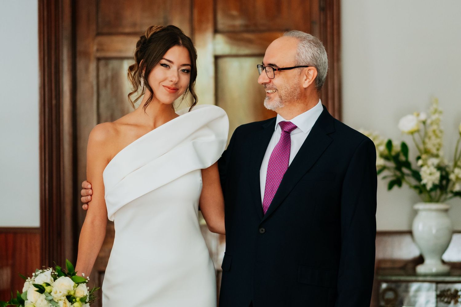 Wedding scene in an elegant room with white decor and wooden trim details.