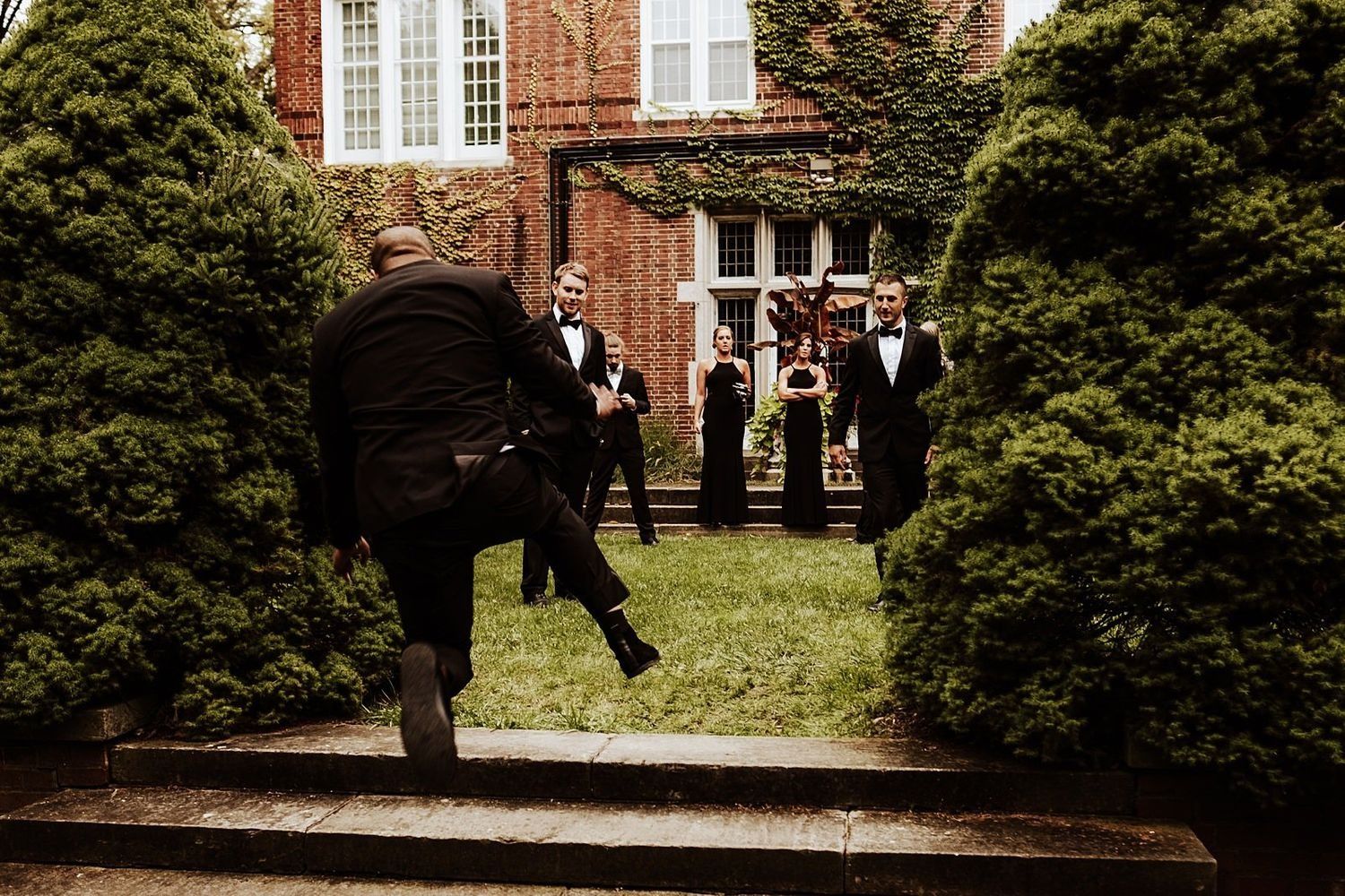 Candid shot of an excited wedding guest jumping for joy during the outdoor celebration in Michigan