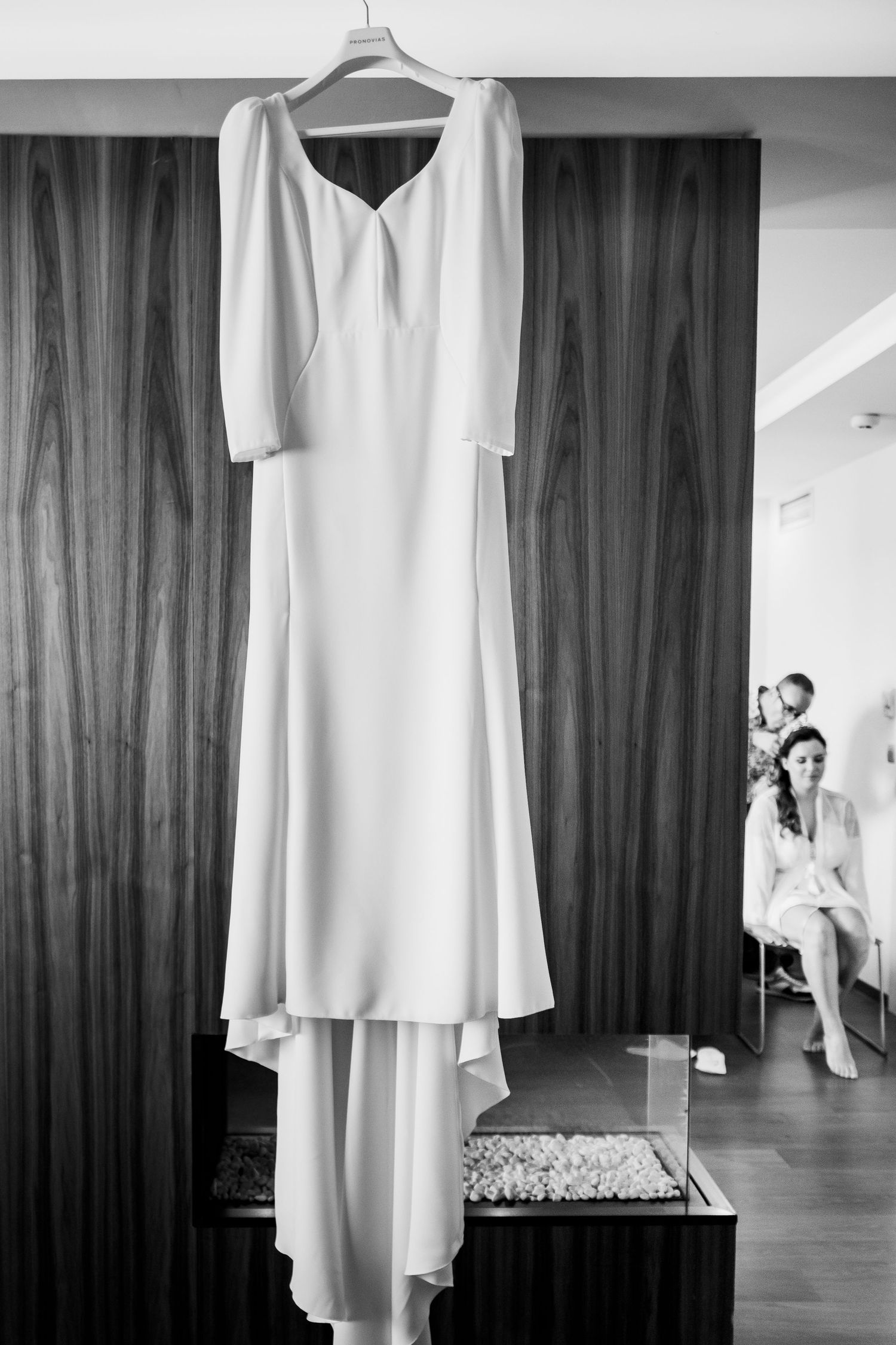 Vestido de novia de Pronovias para Eli colgado en la ventana con luz natural