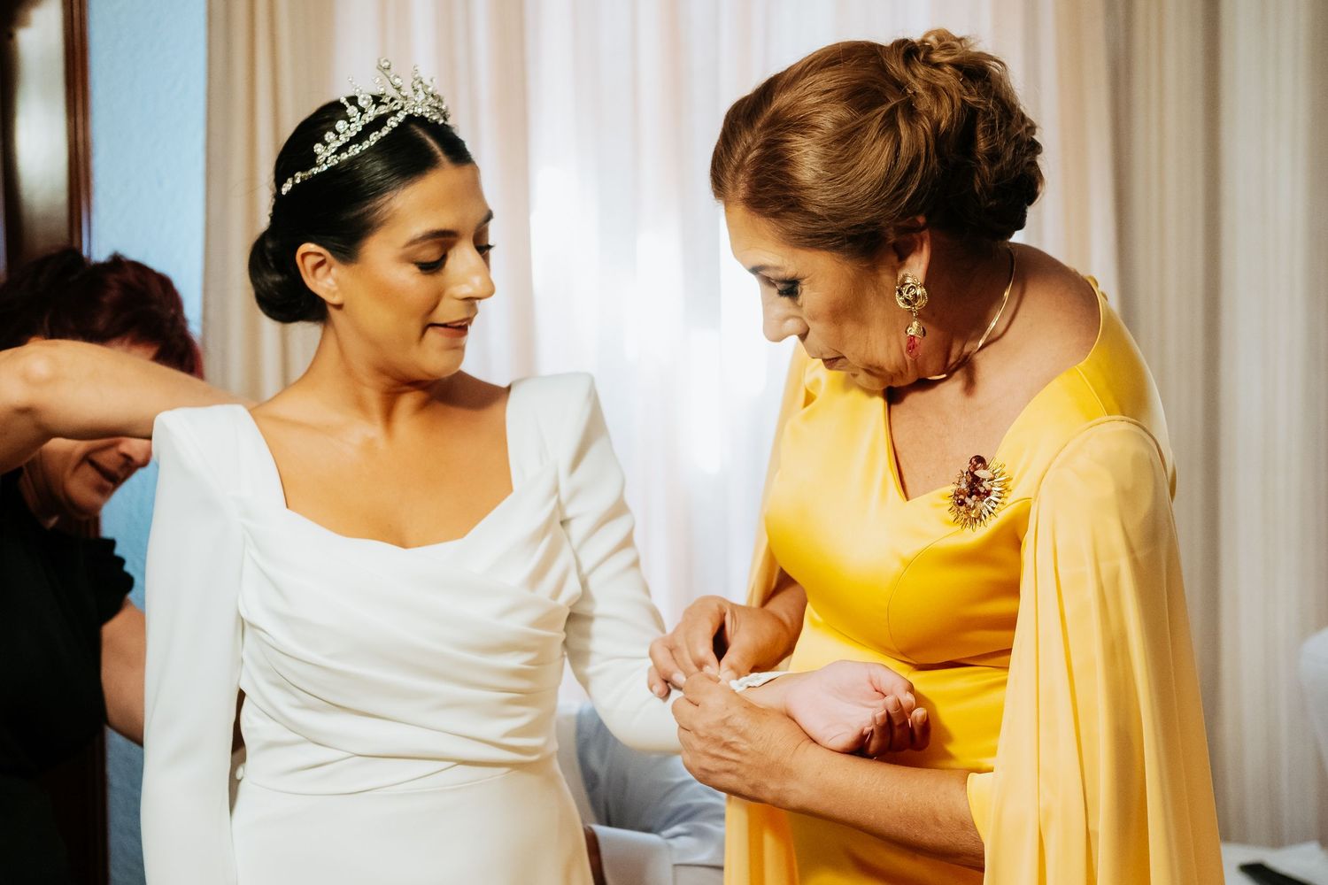 Madre de la novia abrochando los botones del vestido de Inma