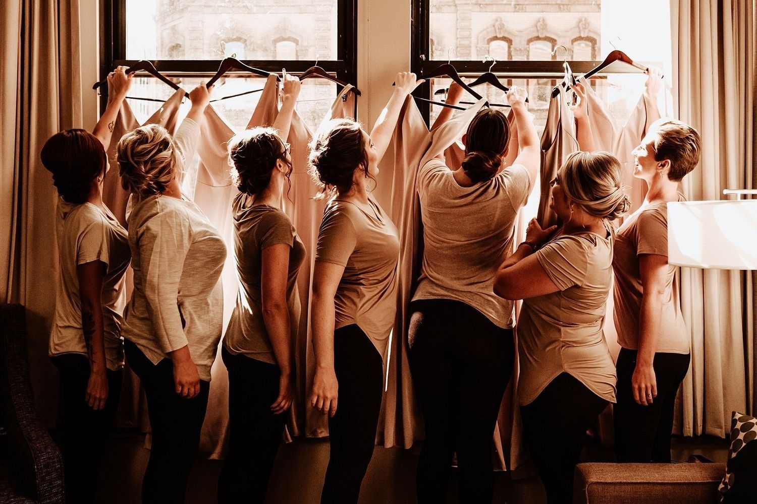 Elegant bridesmaid gowns displayed against the large suite windows in Michigan