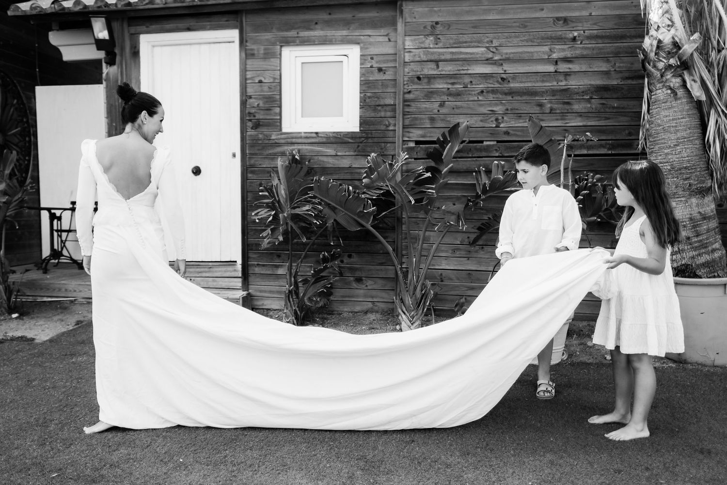Retrato documental de María y Lucas ayudando con el vestido de novia durante la sorpresa blanco y negro Sajorami Beach Laura Roberto Pecino