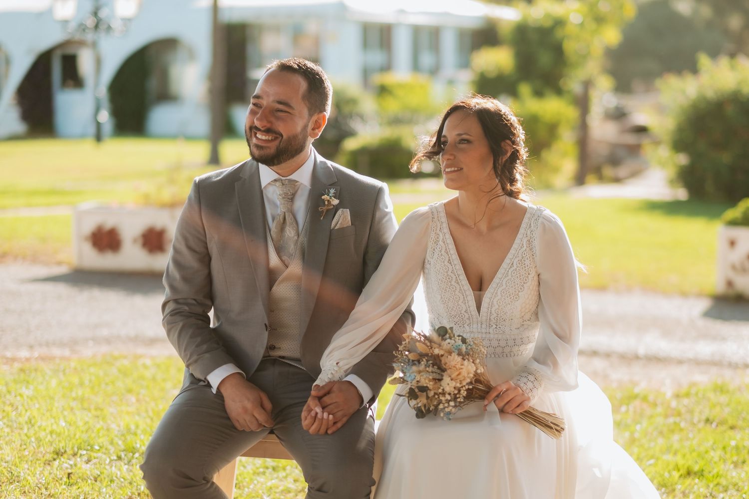 A couple sits together on grass during their outdoor wedding photoshoot, Roberto Pecino fotografo en Soto de Roma
