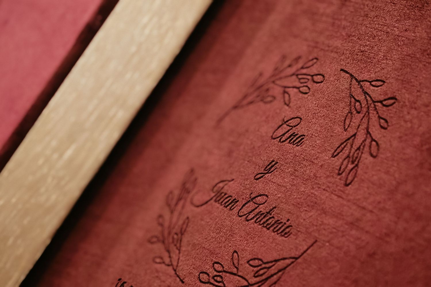 Close-up view of burgundy leather book covers with delicate floral patterns embossed on their surfaces.