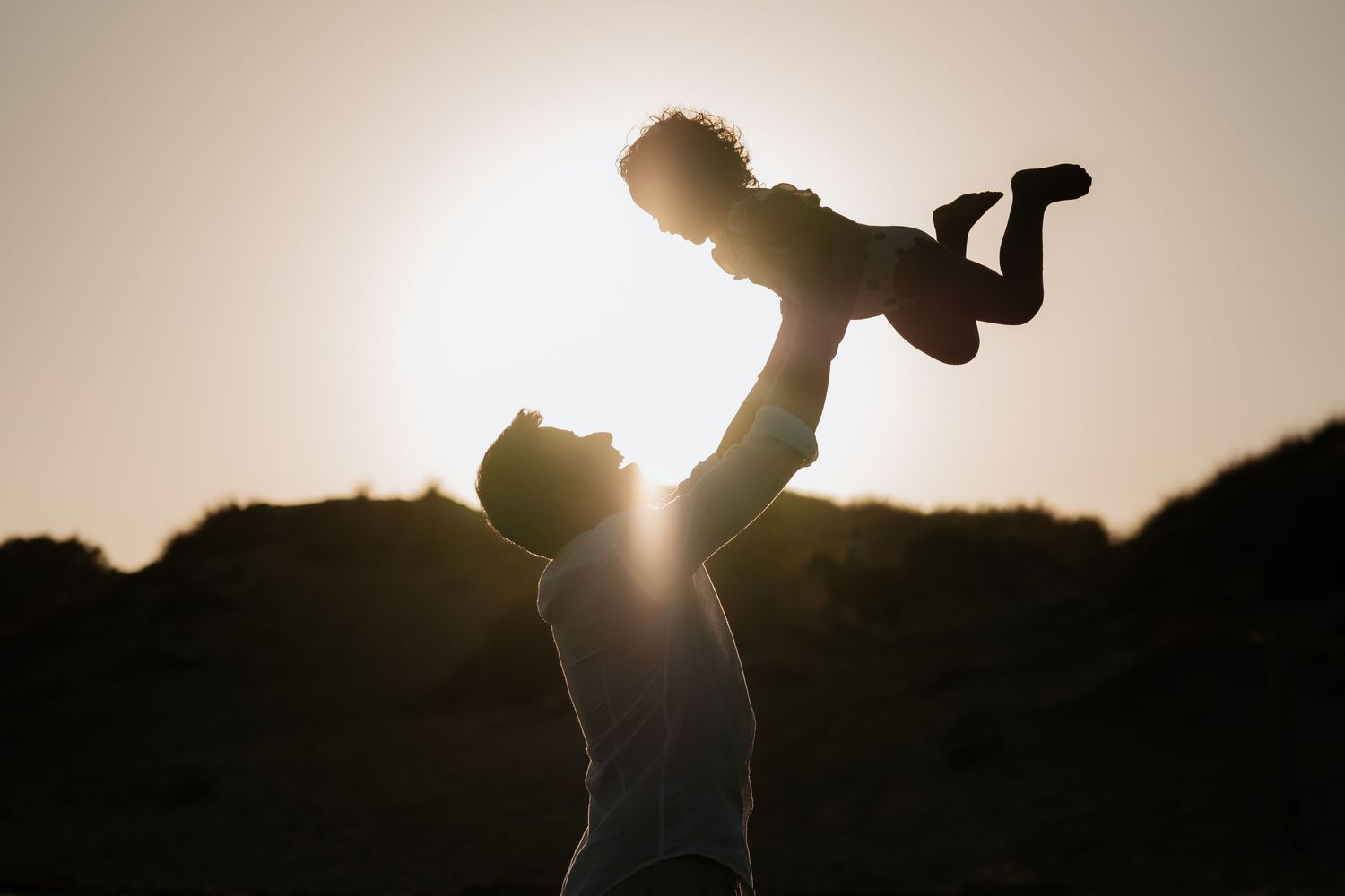 Silhouetted figure performs an energetic dance move against a bright sunset sky backdrop.