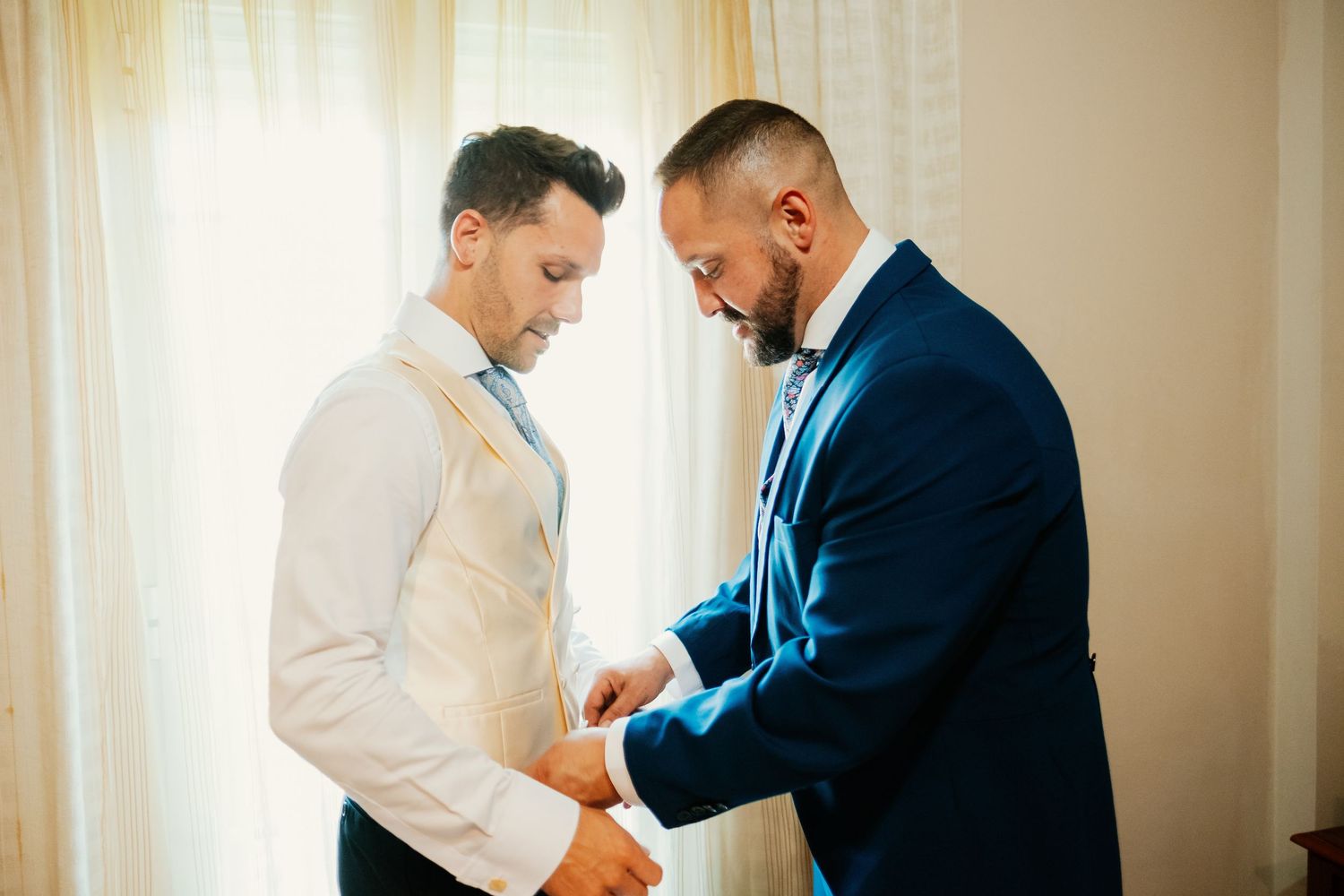 Novio poniéndose el chaleco del traje a medida, luz natural lateral y estilo cinematográfico en Córdoba