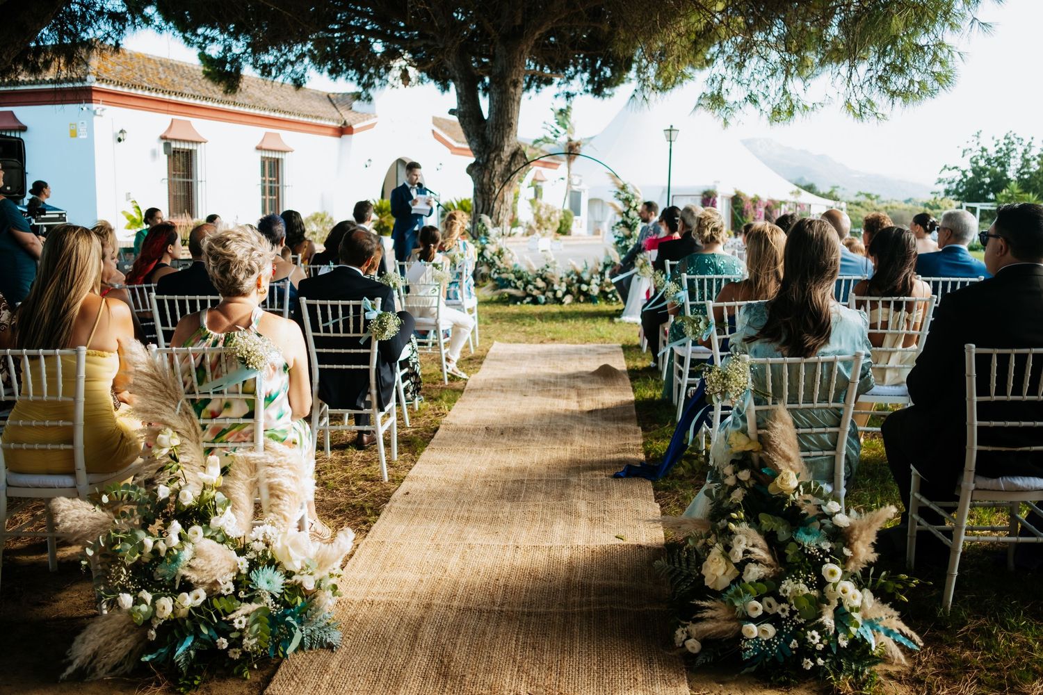 Elegant outdoor wedding reception setup with white chairs and floral arrangements, Soto de Roma