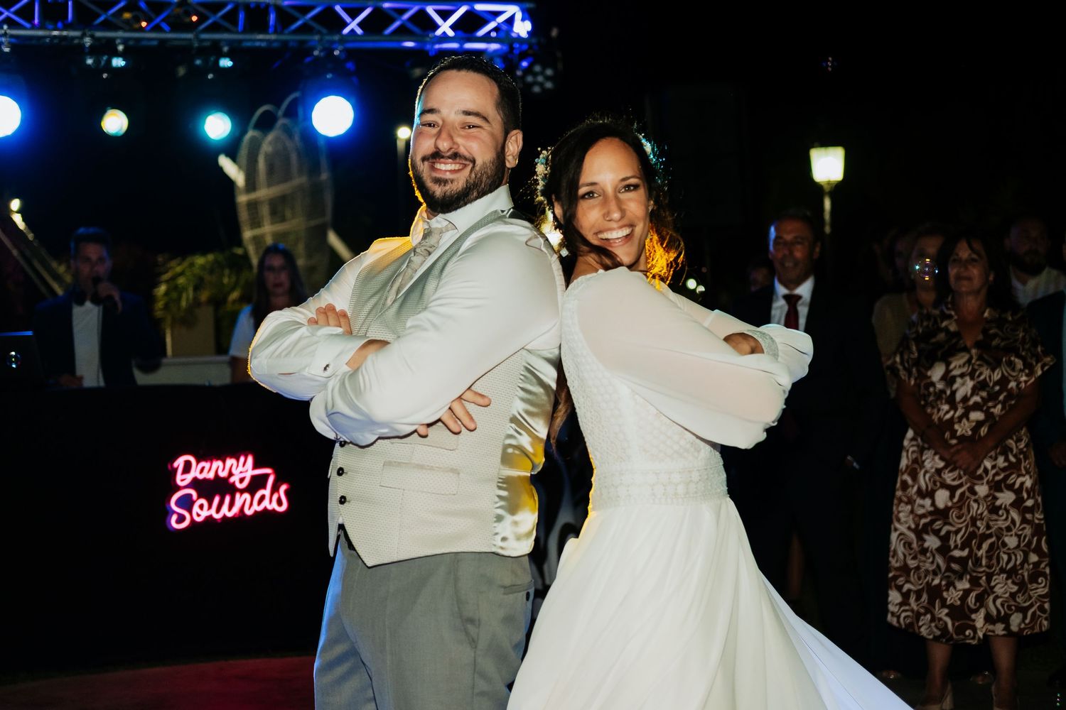 A couple dances together at their wedding reception under blue stage lighting.