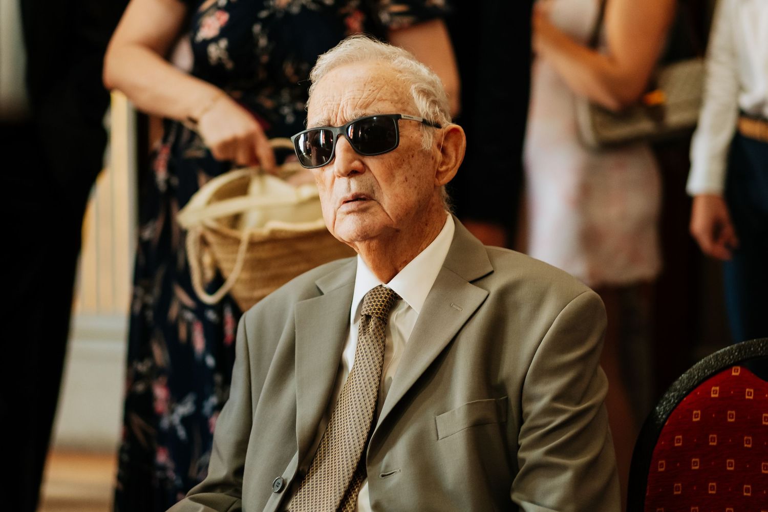 A series of photos showing a person in a suit and sunglasses sitting in various poses at an event.
