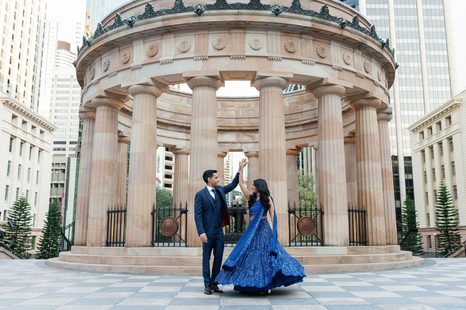 Couple dancing beneath classical downtown rotunda with blue ballgown and formal attire.