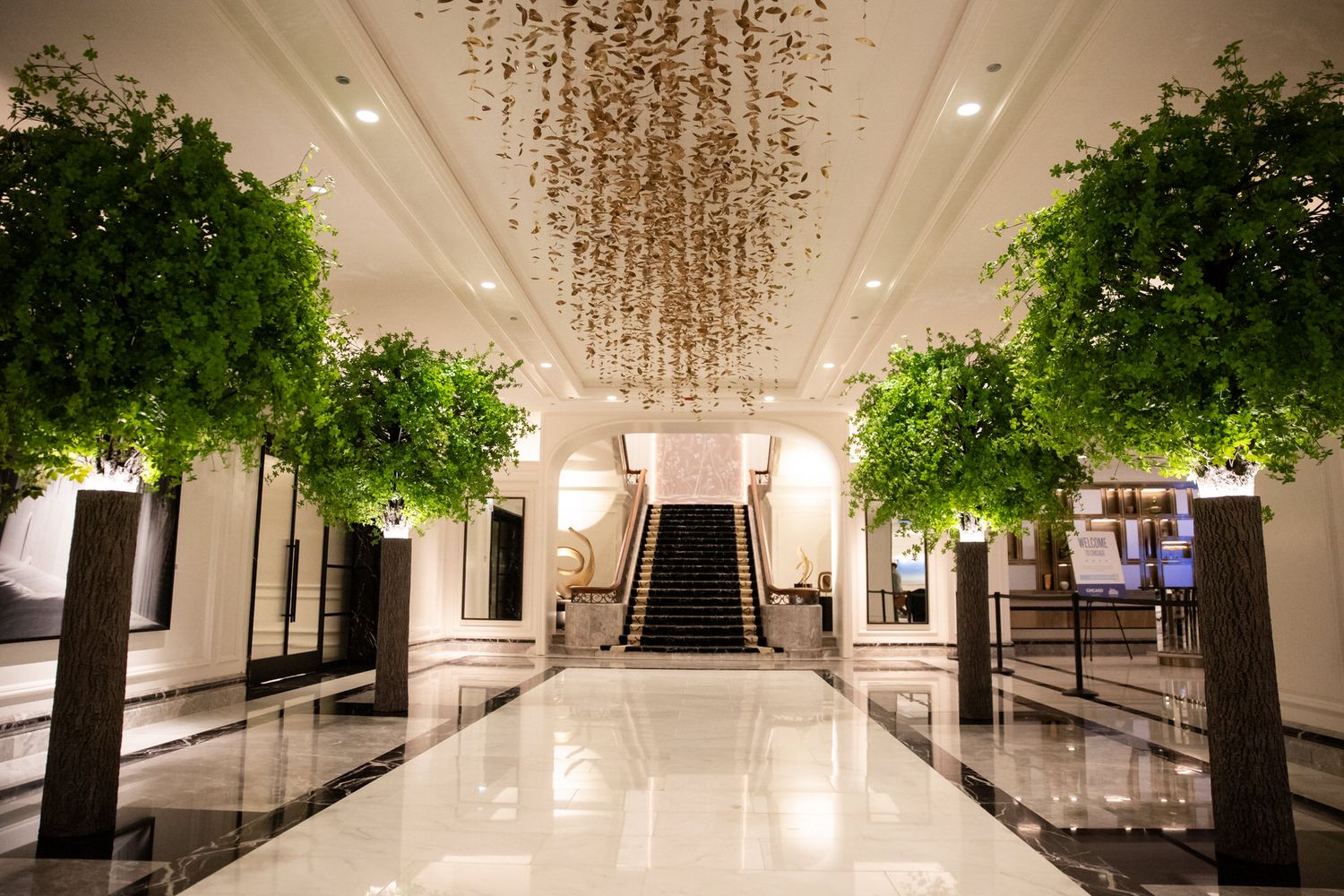 Luxurious hotel lobby interior with crystal chandeliers and lush green plants showcases elegant modern design.