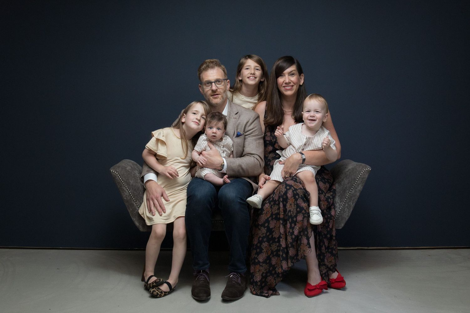 Studio family portrait session showing embracing group sitting together against dark background.