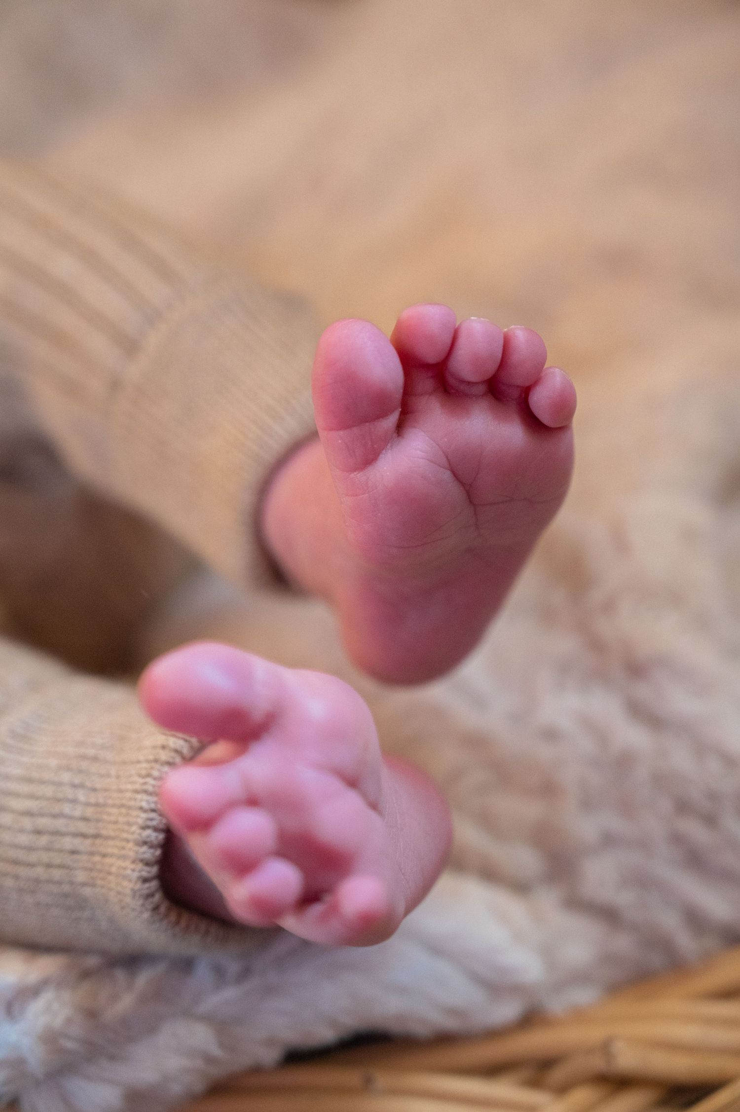 Tiny baby feet resting on a textured knit blanket in warm lighting.