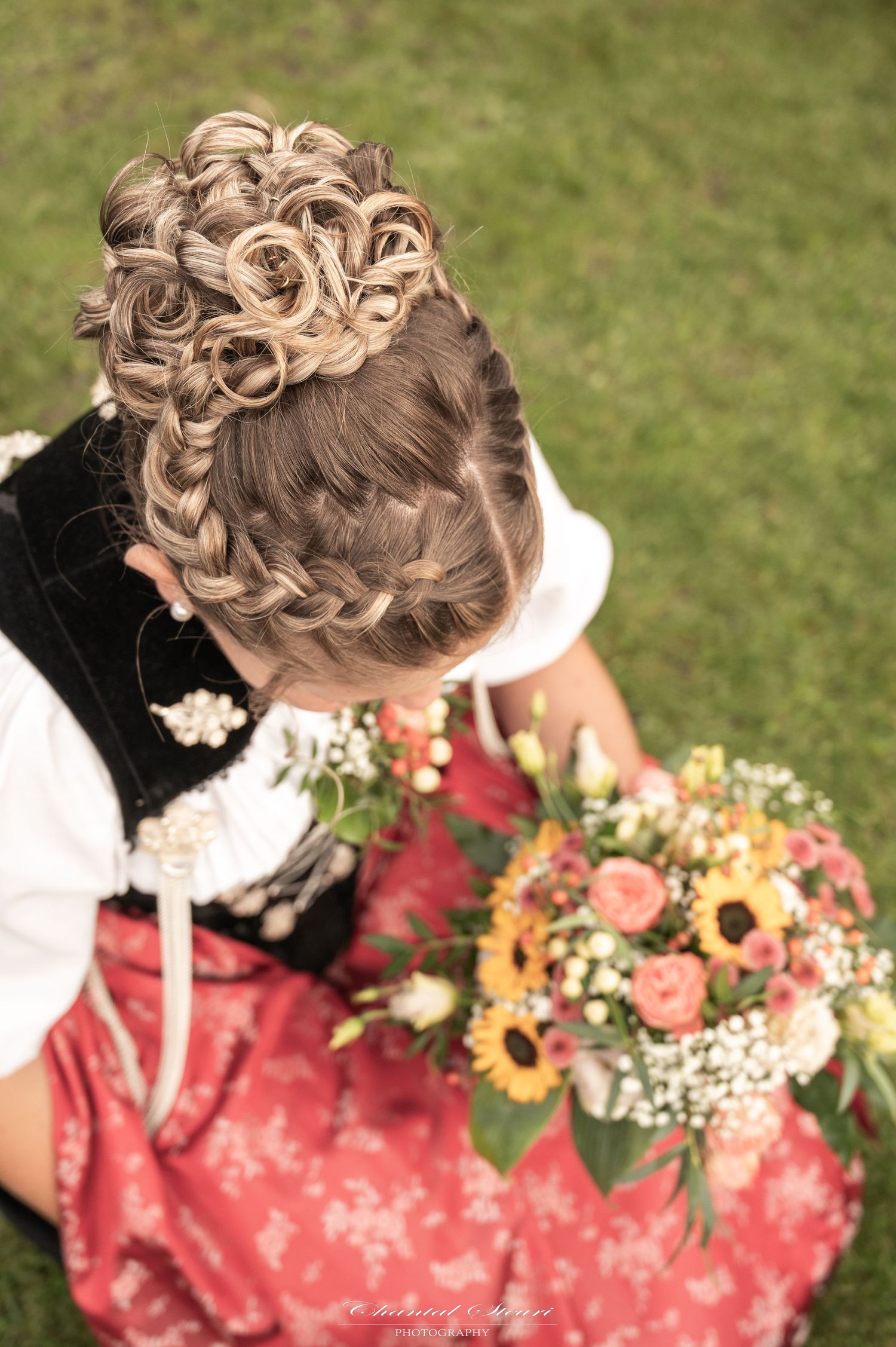 Intricate braided hairstyle with flowers and traditional dirndl dress photographed from above.