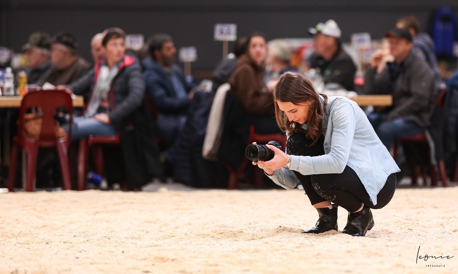 Photographers documenting a livestock competition in an indoor arena.
