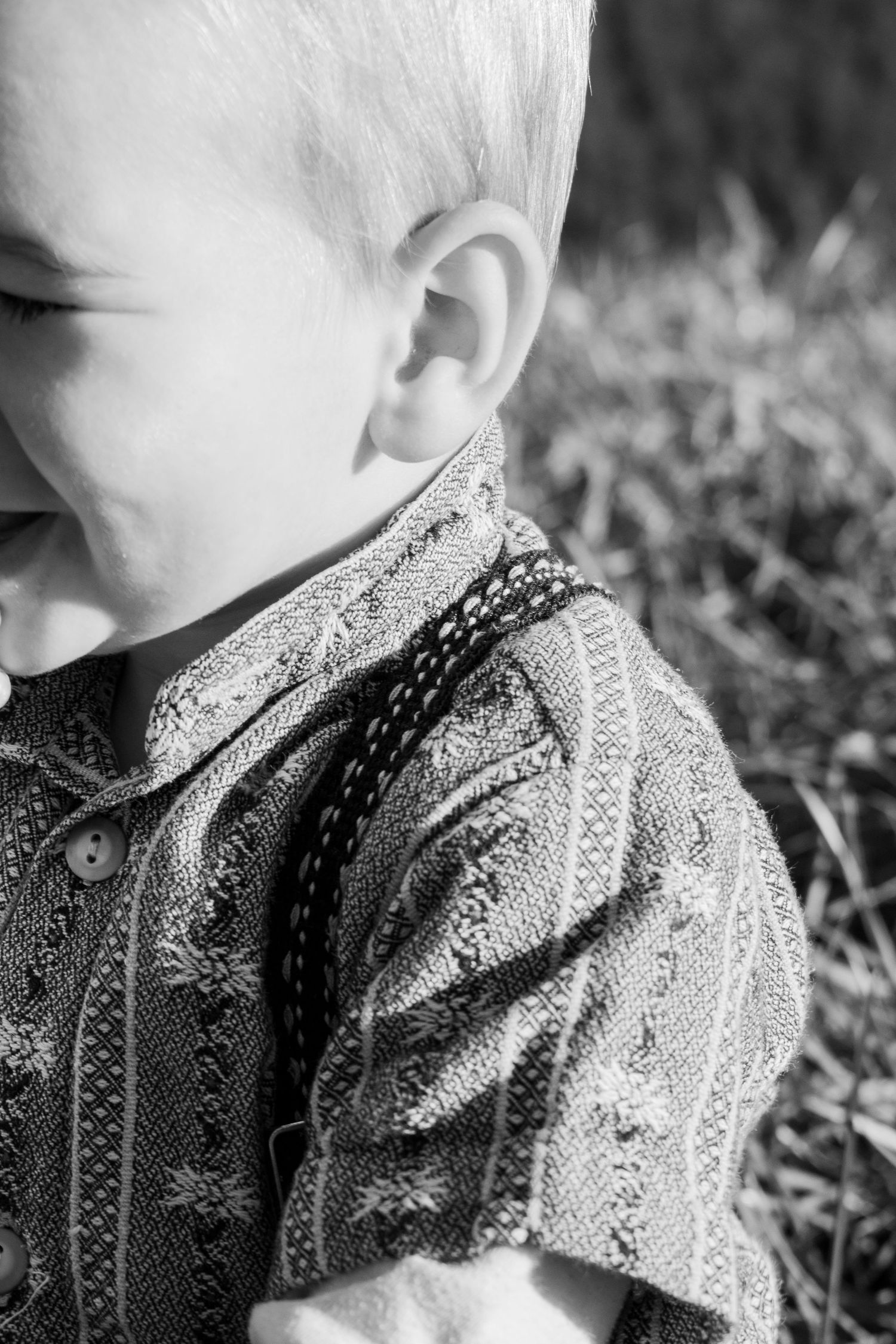 Black and white close-up of child wearing patterned shirt.