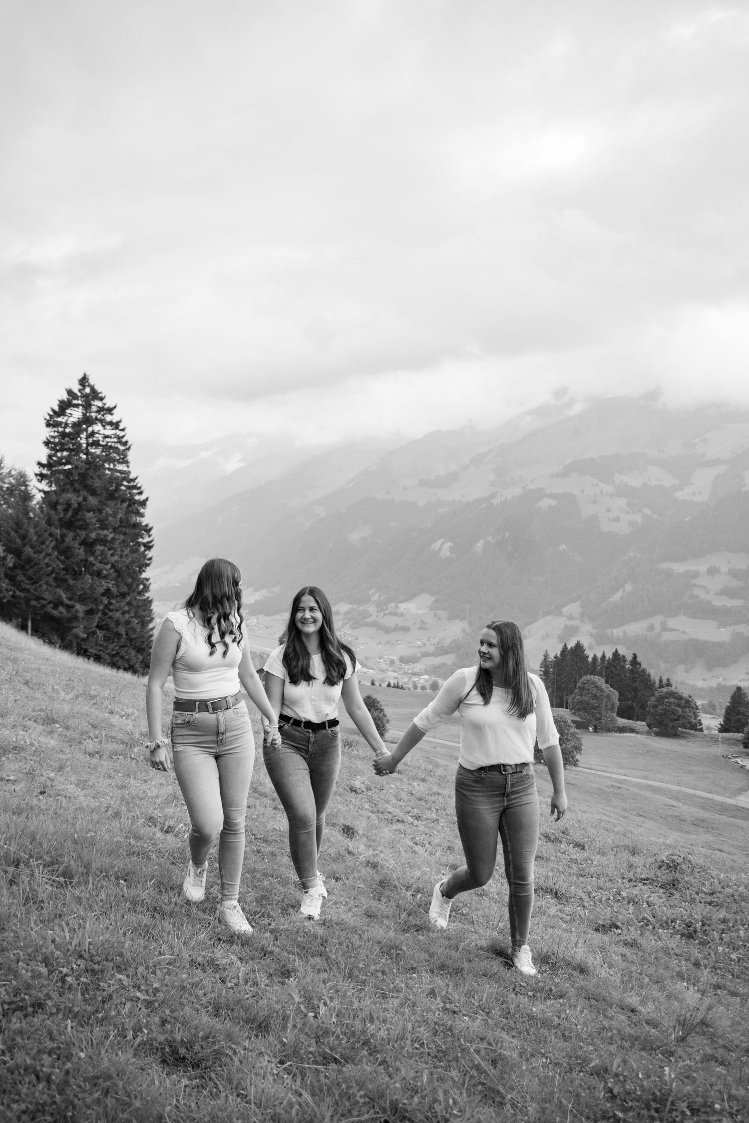 Friends walking together on grassy mountainside with scenic alpine views.