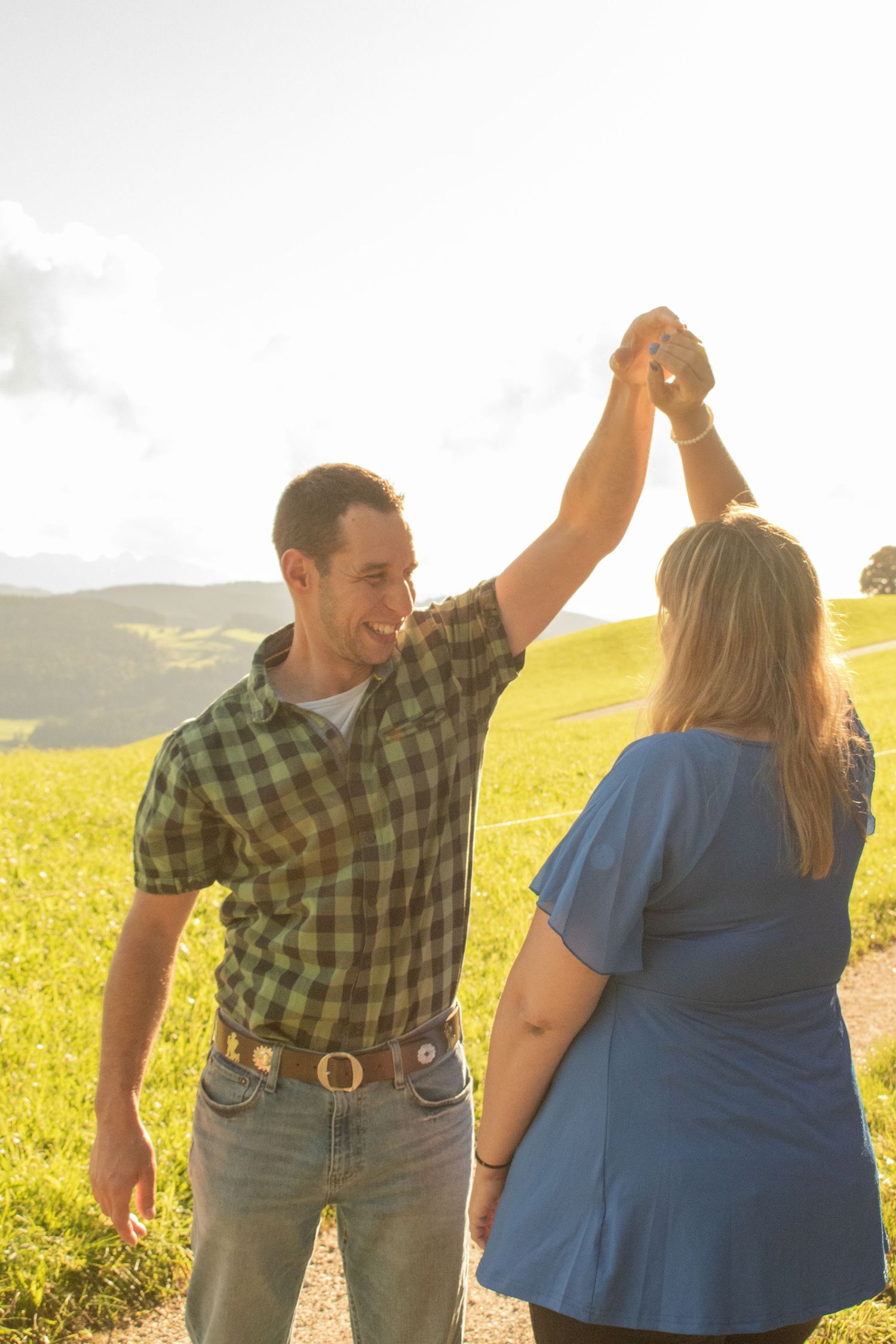 Dancing couple in a sunlit yellow field during golden hour.