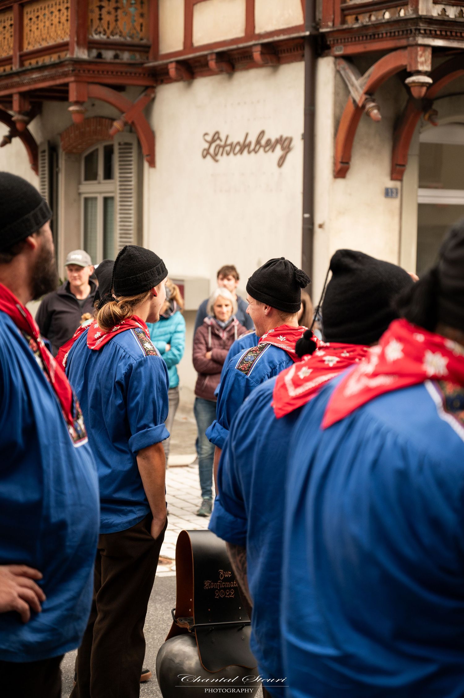 Traditional performers in blue uniforms gathered outside a building marked Leitchberg.