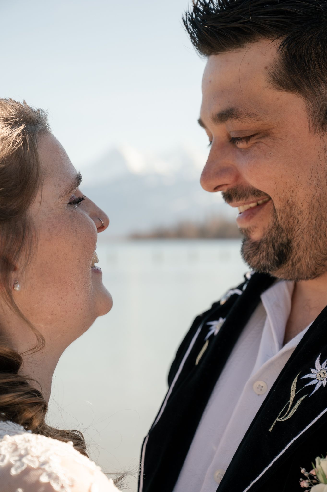A happy couple shares an intimate moment at sunset, with their faces close together and smiling warmly.