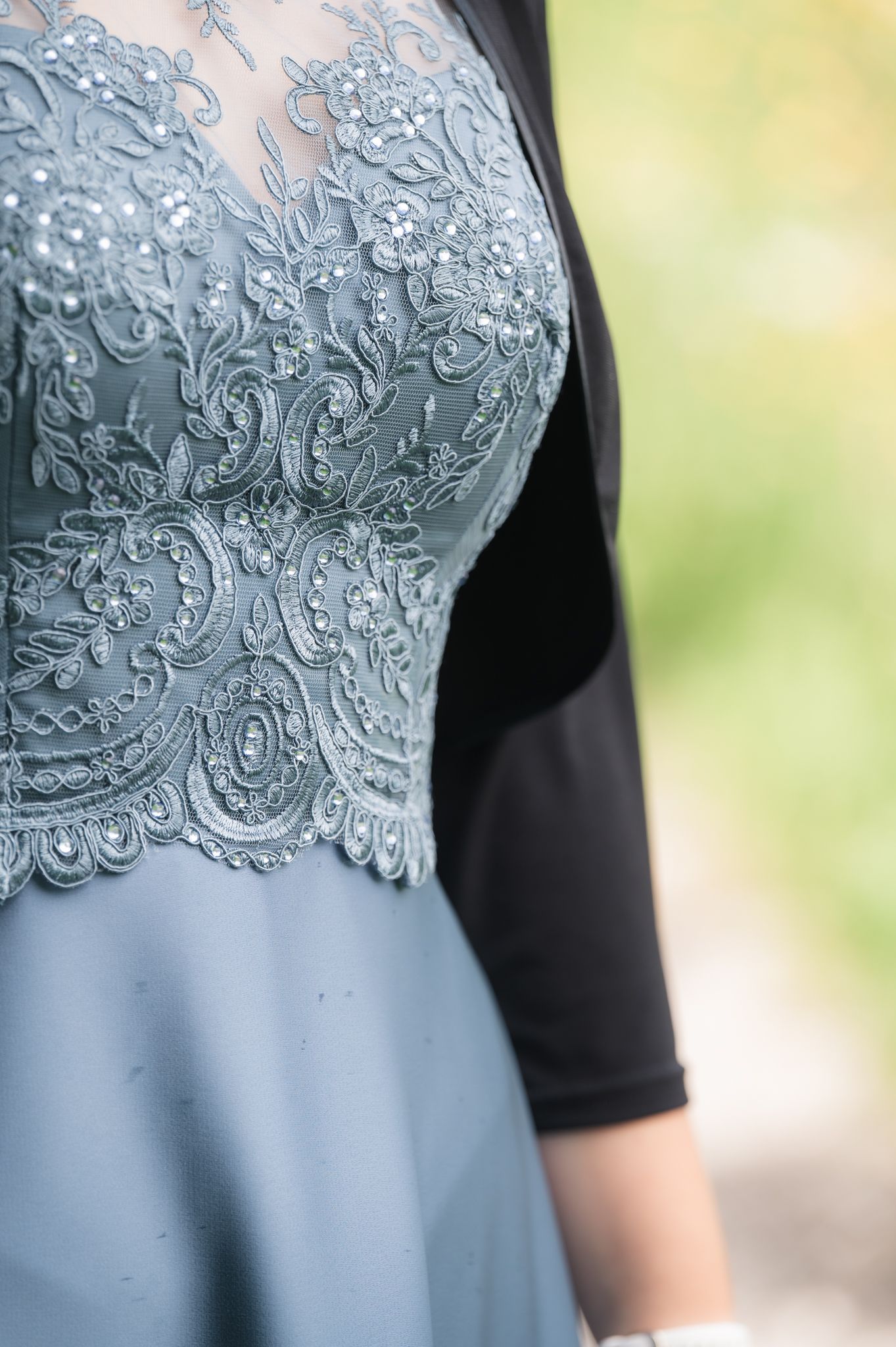 Close-up of an elegant dusty blue lace bodice gown with intricate beaded floral embroidery details.