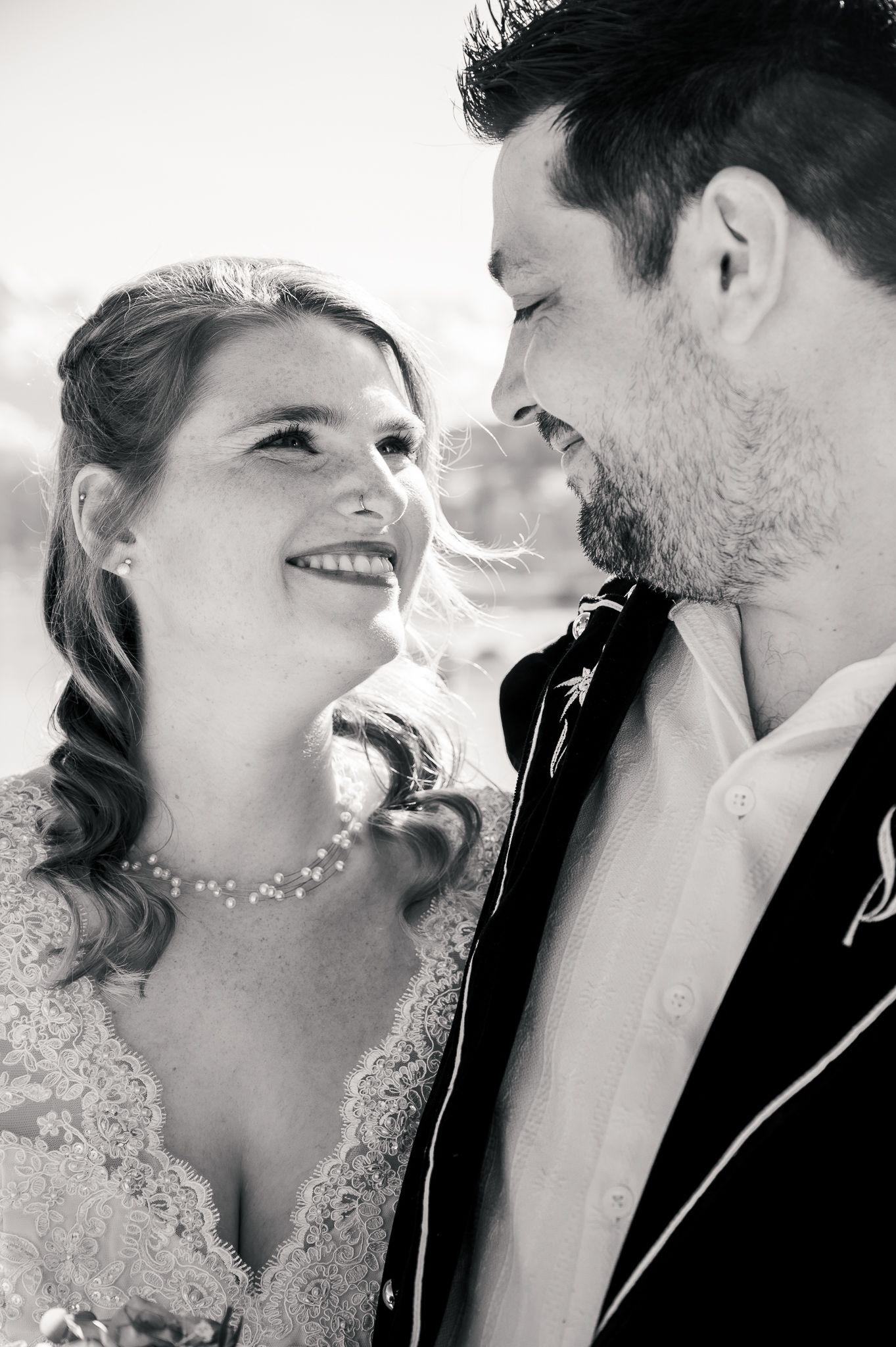 A black and white wedding photo showing a tender moment between newlyweds smiling at each other.