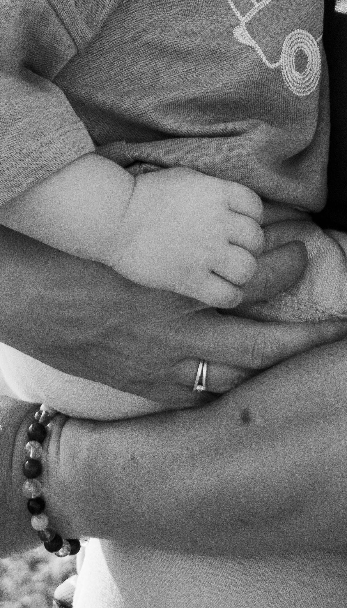 Close up of intertwined hands with wedding rings and bracelets showing affection.
