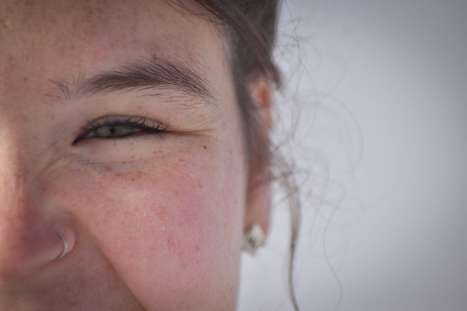 Extreme close-up portrait showing partial facial features in soft lighting.