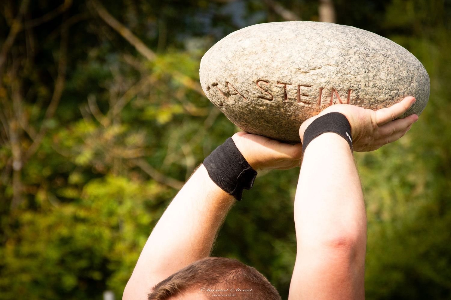 Person balancing large stone on their legs during outdoor exercise.
